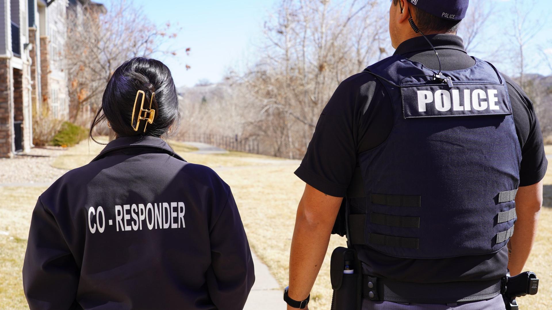 Co-responder and police officer walking down a suburban path.